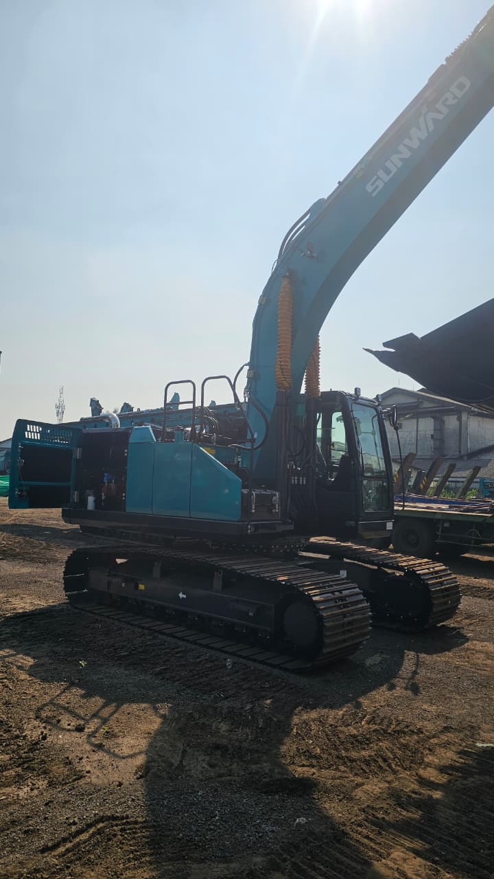 Excavator dengan boom terangkat di area material
